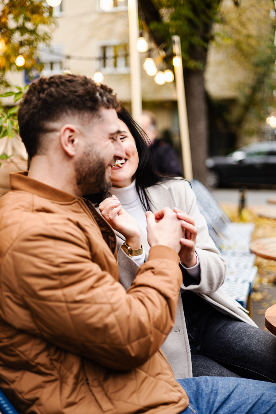 Para śmieje się. W tle widać światełka i jesienny krajobraz.